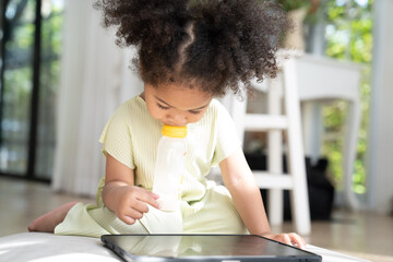 African American little girl playing and using a tablet at home - 764461466