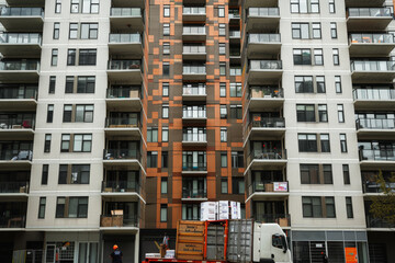 Movers unloading boxes from a container truck at a high-rise apartment building.