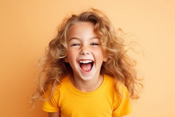 Portrait of a happy little girl with blonde hair over orange background