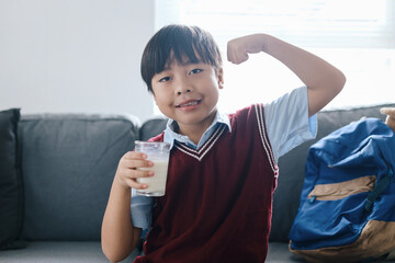 School Boy Wearing Uniform and Showing Strong Gesture While Drink a Milk Before Going To School 