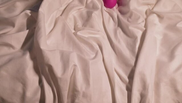 female hand with a pink vibrator for masturbation and satisfaction in sex. Sex toy in hand woman girl on a bed