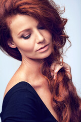 Fototapeta premium Beauty, relax and woman in studio with haircare, natural keratin glow and healthy hairstyle. Growth, shine and confident girl with red hair, wellness and luxury salon treatment on blue background