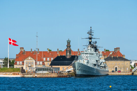 Ships of the Marinestation Holmen naval base on the harbor on a clear blue sky day with the Danish flag full mast