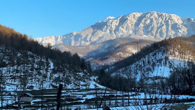 mountain landscape in rural life countryside village in Hyrcanian forest local people agriculture is rice paddy farm field forest hills covered by snow and sun light with warm temperature in sunset