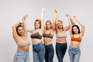 Group smiling multiracial women wearing sexy bras, stylish jeans isolated on white background