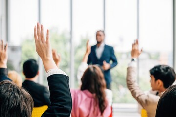 At a corporate event business professionals participate in a conference and convention. Raised hands showcase active involvement in a meeting training seminar and discussions.