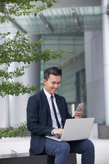 Asian business Man using his laptop outdoors.