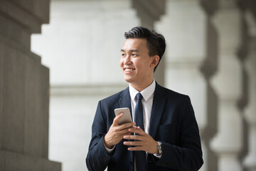 Asian business Man using his Smart phone outdoors.