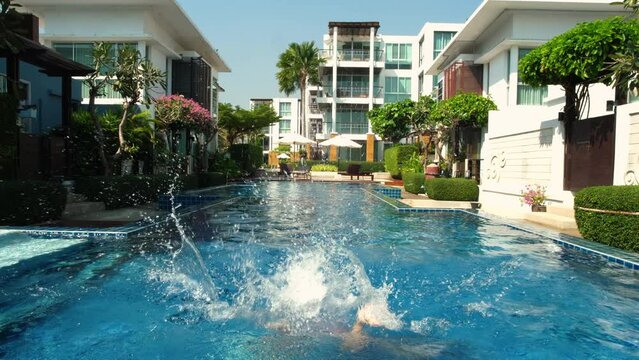 Young Girl Mid-Jump Into a Sunny Resort Pool at a Luxury Villa