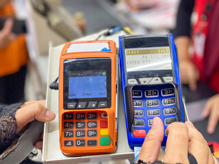Hand of customer pushing password button of mobile EDC to make a payment on groceries shopping 