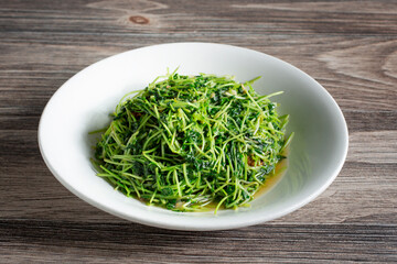 A view of a plate of sauteed pea sprouts.