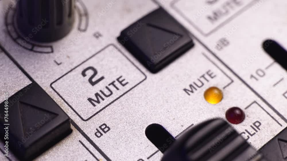 Poster muting channel 2 on mixing audio console, pressing button mute, macro close up