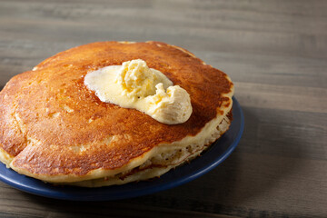 A view of a stack of pancakes, with a dollop of melting butter spread.