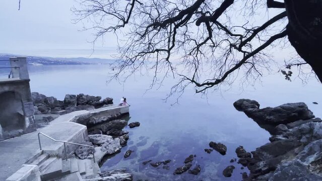 Couple sitting on Sea shore wide Lovran, Opatija, Croatia