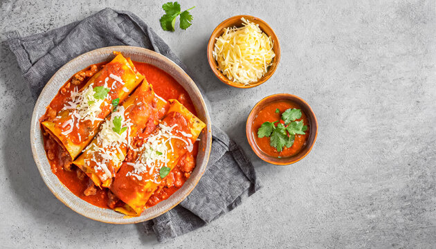 Beef enchiladas. top view shot of Beef enchiladas in tomato sauce and cheese on grey plate with copy space