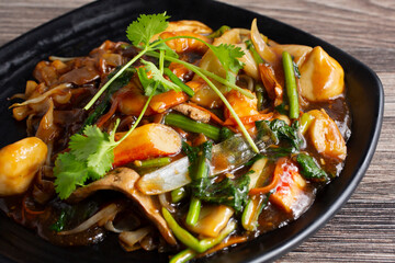 A closeup view of a plate of stir-fried white noodles.