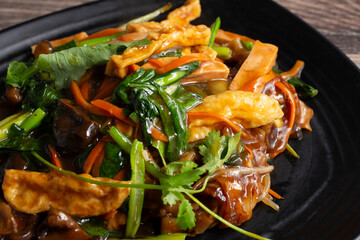 A closeup view of a plate of stir-fried white noodle with veggies.