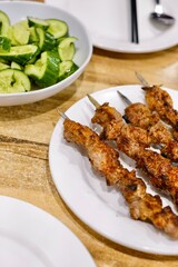 A plate of Xinjiang-style spiced cumin lamb skewers with garlic cucumber salad at Apandim Uyghur Restaurant in Burwood Chinatown - Sydney, NSW