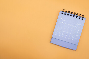 Blue desk calendar for MAY 2024 isolated on orange background. Calendar concept with copy space. Flat lay. - obrazy, fototapety, plakaty