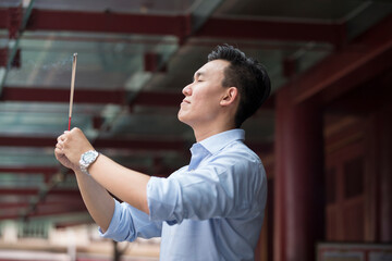 Asian man praying in a temple.