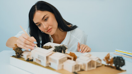 Closeup portrait image of young beautiful architect focus on measures the architectural model with...