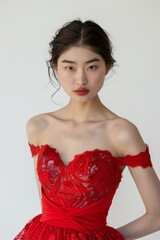 Portrait of a pretty young woman super model of Japanese ethnicity donning an elegant red cocktail dress with intricate lace detailing, a cinched waist, and a flared skirt