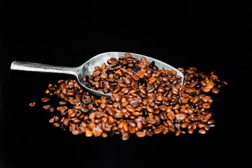 Coffee beans in the bottle spread out of bottles put on sack in darkness background.