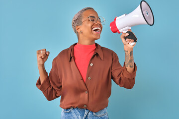 Young overjoyed joyful African American woman makes victory gesture and shouts into megaphone...