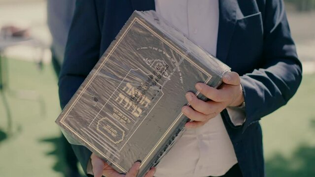 A Jewish man holds a closed Torah book in his hands. High quality FullHD footage