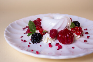 White cream cake with fresh berries on white plate. Isolated on beige background