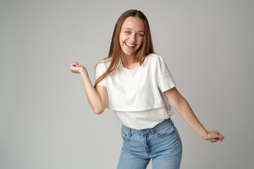 Young smiling girl dancing having fun on gray background