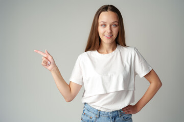 Young woman wearing casual outfit pointing empty space on gray background