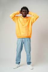 African Man in Yellow Hoodie Holding Head and Smiling