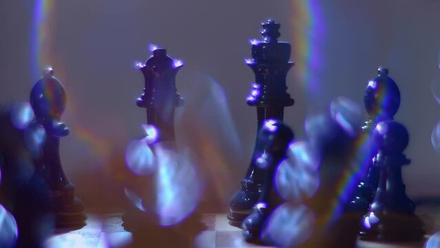 Lacquered chess pieces sparkle in the ray of light and the light source creates a beautiful rainbow flare. Closeup