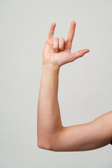 Male hand gesturing rock and roll on gray background