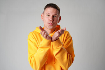 Young man blowing a kiss against gray background studio shot