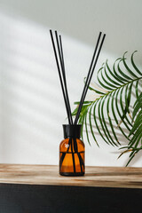 Aromatic Reed Diffuser on Wooden Table With Vibrant Green Leaves Against White Background