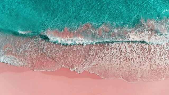 Close-up view of a calm wave on a paradise beach in the Caribbean. Ocean waves of blue and aquamarine colors on pink sand. Idyllic sea beach background.