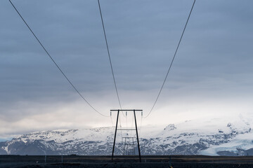 Electricity power lines running towards distant snow capped mountain blend of technology and nature landscape in Iceland