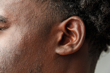 Close-Up View of African Mans Hair and Ear Against a Grey Background
