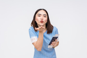 Fototapeta premium Asian woman blowing a kiss with passport and boarding pass in hand, isolated on white