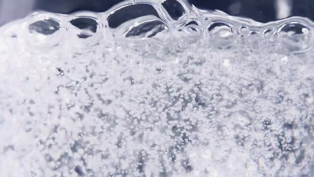 Bubble Game. Slow Motion at a rate of 480 fps. Carbonated water is poured into the glass on a dark blue background
