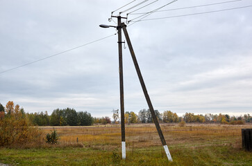 Closeup of power pillar at rural terrain. Power line post with electricity cables against sky and field