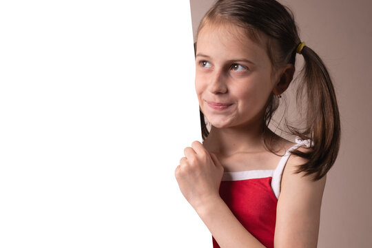 Portrait of beautiful attractive young girl behind white blank banner or empty copy space advertisement board on brown background, Copy space for text or design. Horizontal image.