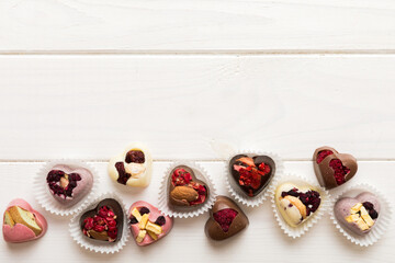 chocolate sweets in the form of a heart with fruits and nuts on a colored background. top view with space for text, holiday concept