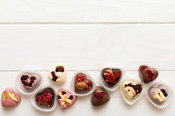 chocolate sweets in the form of a heart with fruits and nuts on a colored background. top view with...