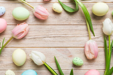 Happy Easter composition. Easter eggs on colored table with yellow Tulips. Natural dyed colorful eggs background top view with copy space