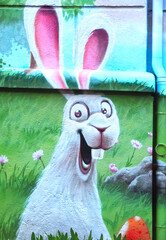Graffiti of a happy Easter bunny in a meadow on a house wall