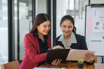 Two women are sitting at a table, one of them is holding a piece of paper