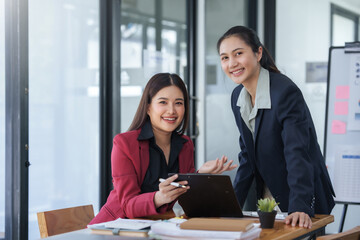 Two women in suits are smiling at the camera